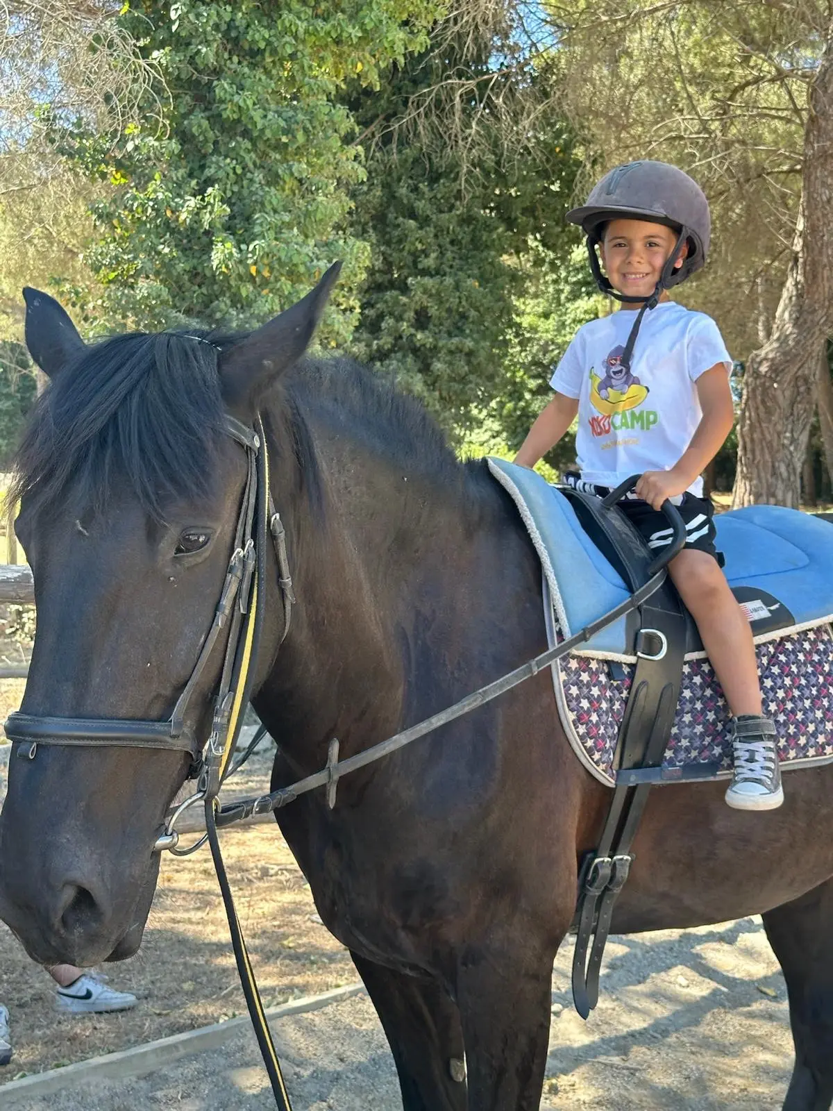 A child in the saddle at KokoCamp, wearing a helmet
