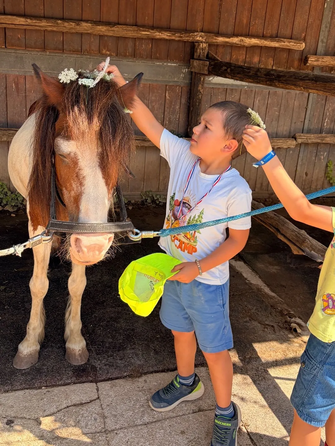 A boy decorating a pony's mane with flowers
