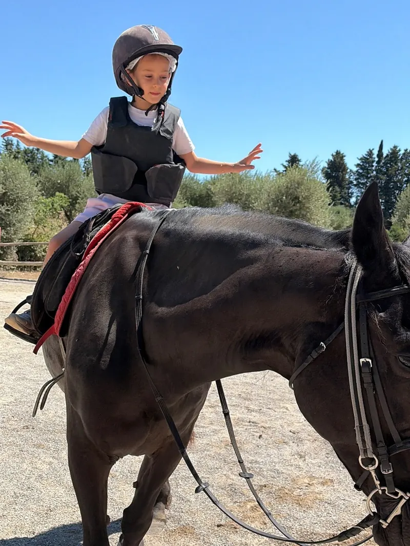 Una bambina in sella a braccia aperte al KokoCamp