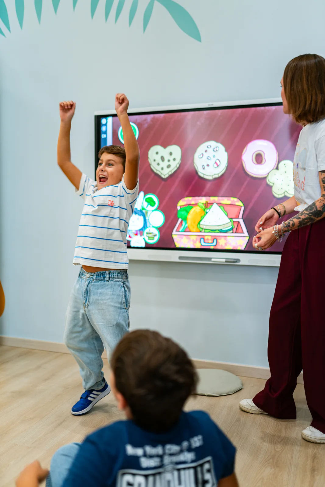 A child cheering with arms raised in front of the interactive whiteboard