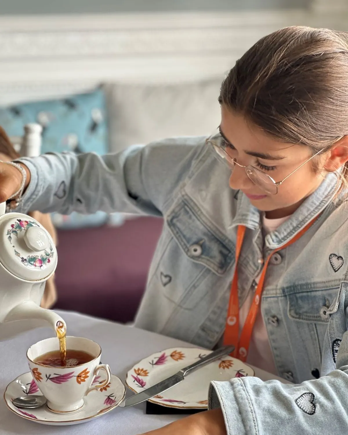 Ragazza versa il tè da una teiera a fiori durante un tradizionale tea time inglese in vacanza studio