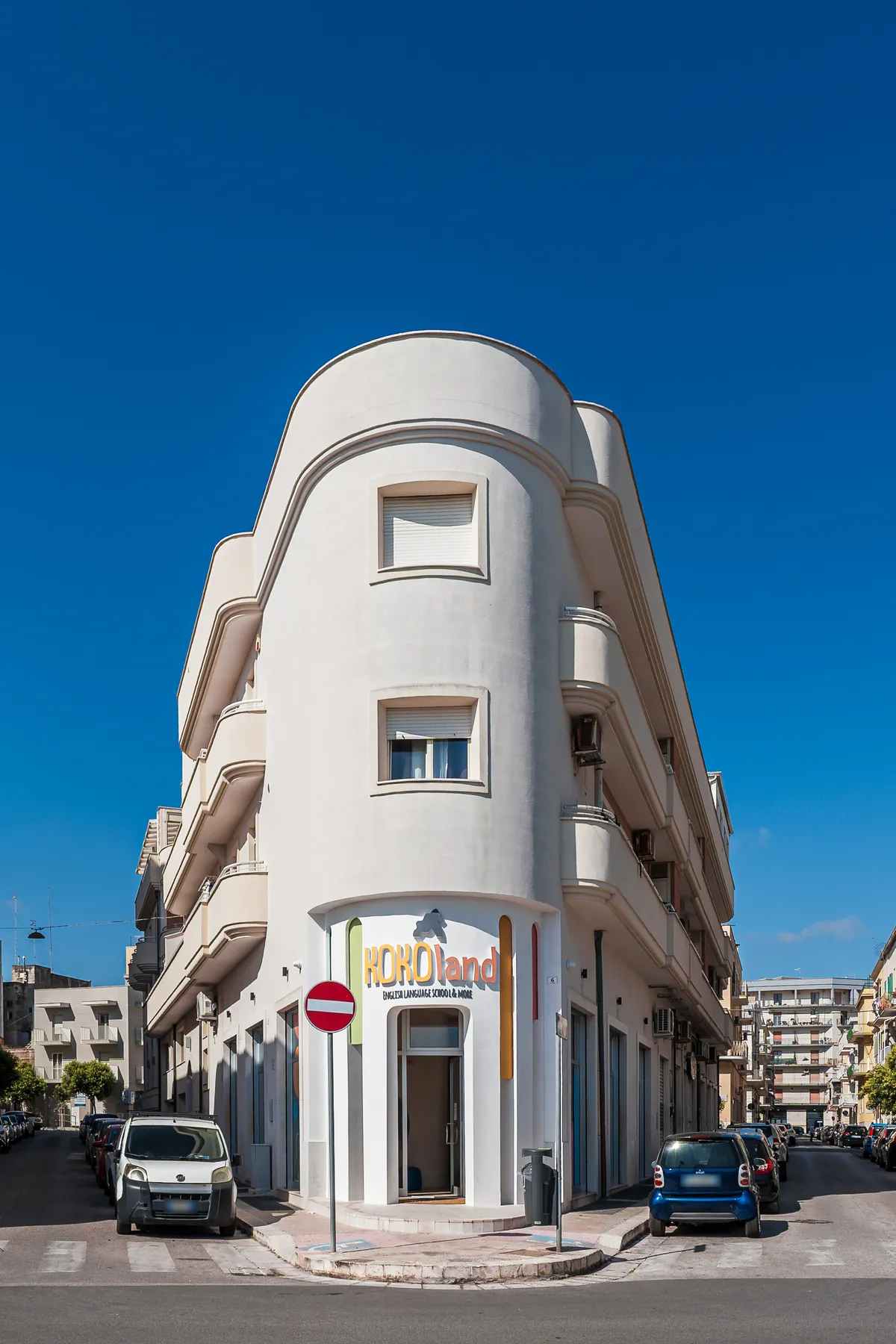 The rounded facade of the KOKOland school in Monopoli under a blue sky
