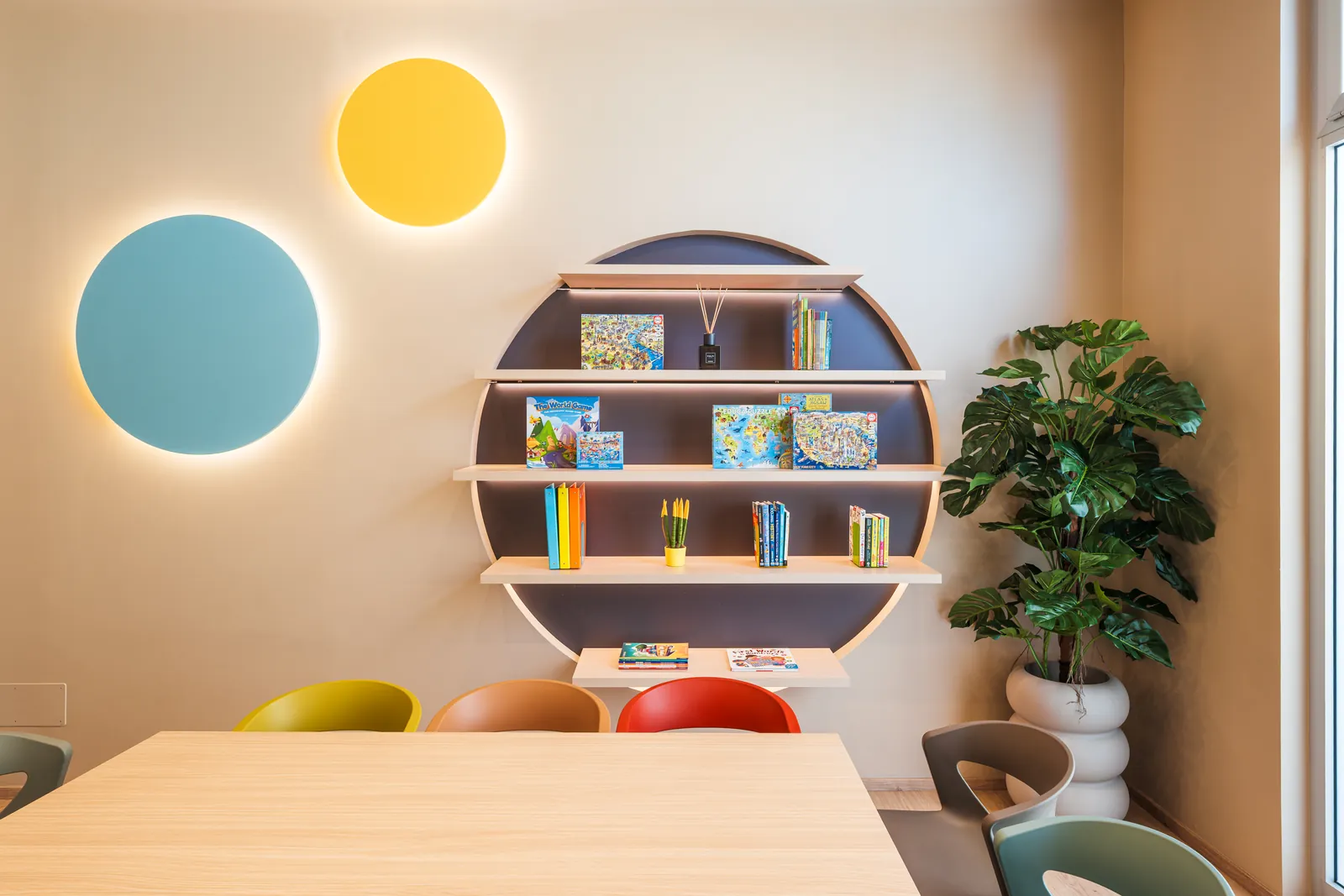The round bookcase full of books and games between two circles of light