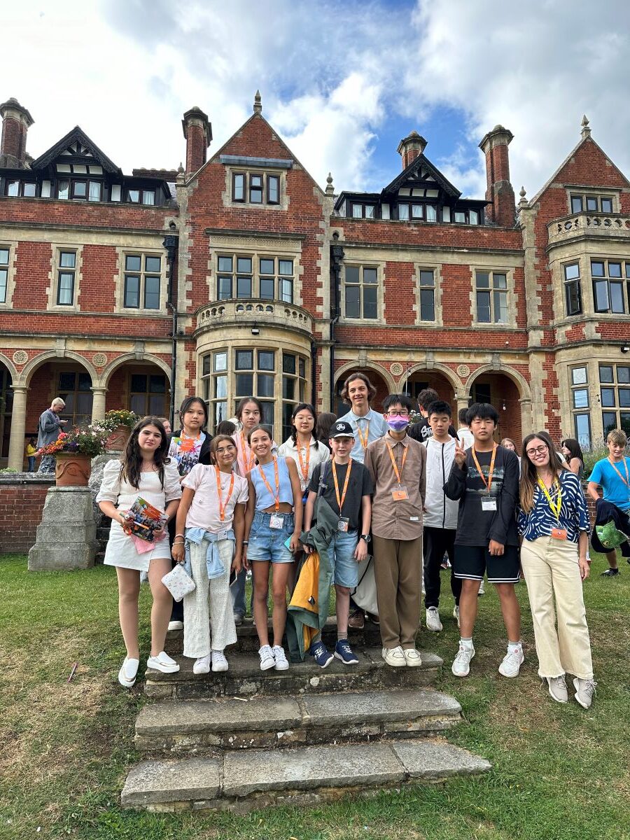 A group of teenagers on their study holiday posing in front of a historic English house