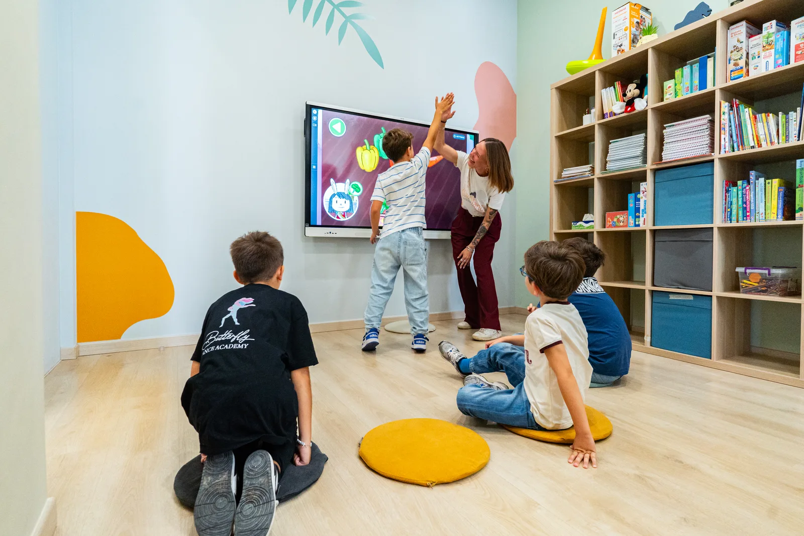 Children sitting on colourful cushions in front of the interactive whiteboard in a KOKOland classroom in Martina Franca